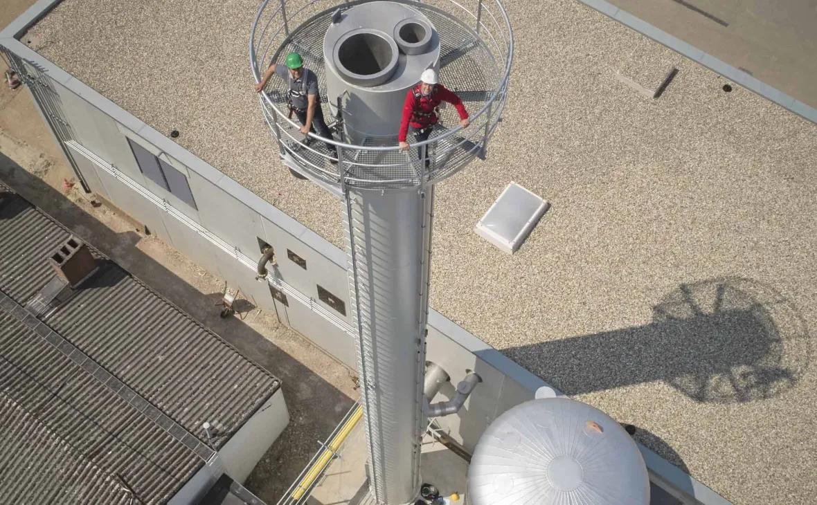 Blick aus der Vogelperspektive auf das Gebäude mit Schornstein und Pufferspeichern, in dem das erste Blockheizkraftwerk installiert ist