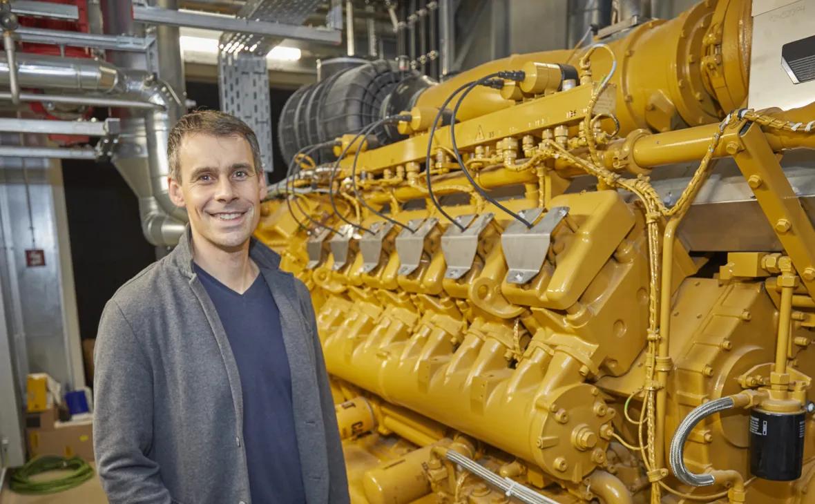 Innenansicht mit Christian Linz vor dem Verbrennungsmotor, der Erdgas verbrennt und dadurch Strom produziert. 