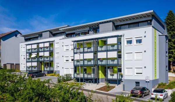 Modernisiertes Mehrfamilienhaus mit Balkonen und Parkplätzen.